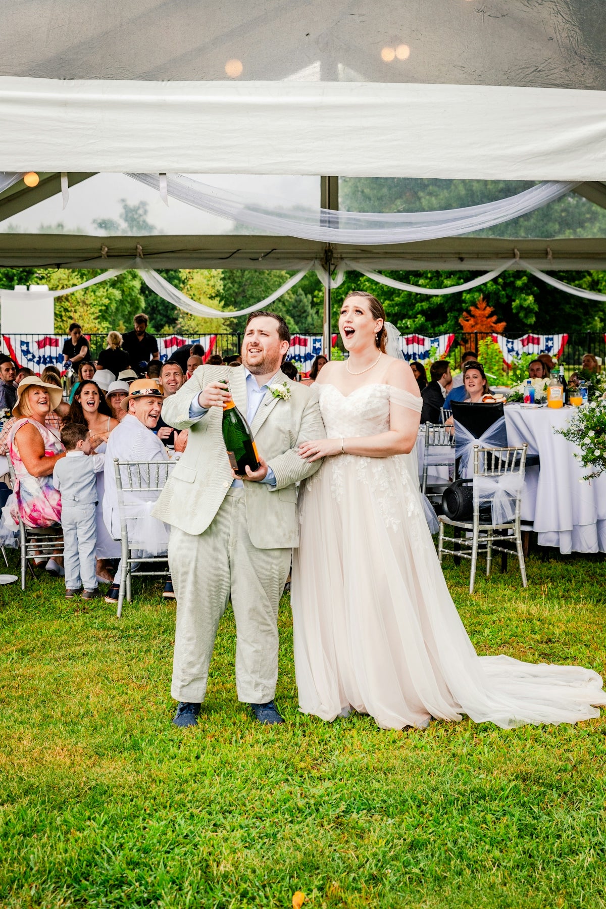 a bride and groom holding a bottle of champagne