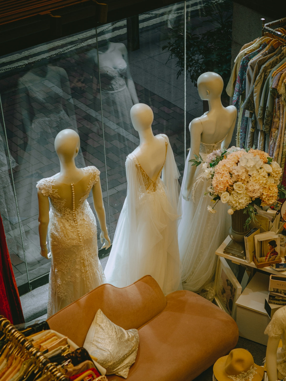 Mannequins display elegant white dresses in a boutique window.